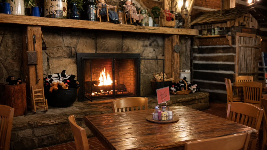 Rustic fireplace dining area inside Log Cabin Pancake House in Gatlinburg with a warm wooden breakfast table and Smoky Mountain lodge atmosphere.