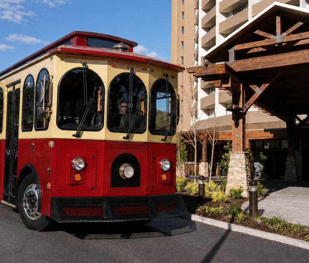 Red-and-cream Gatlinburg trolley approaching The Park Vista hotel entrance
