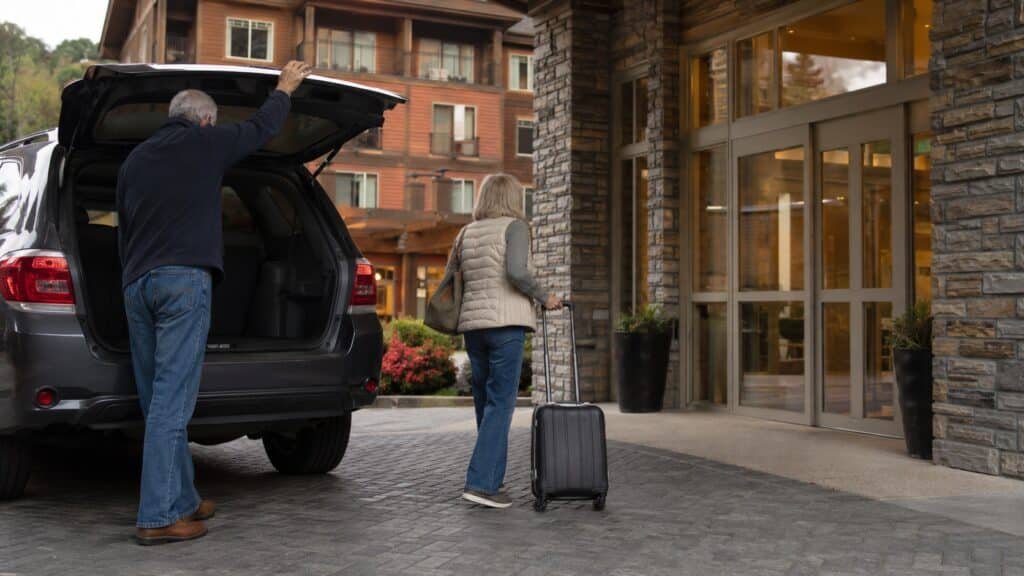 Older couple unloading luggage from an SUV at the entrance to Hilton Garden Inn Gatlinburg
