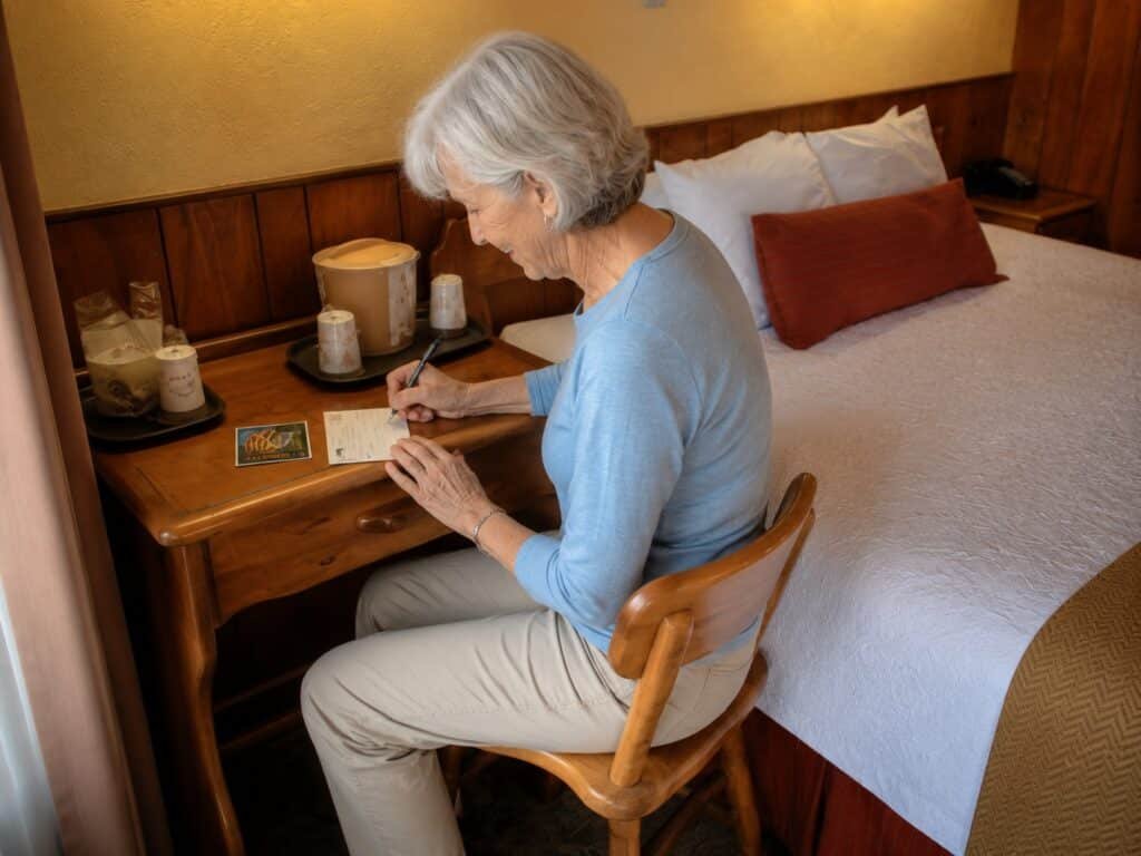 Guest writing a postcard at the desk inside a room at The Historic Gatlinburg Inn