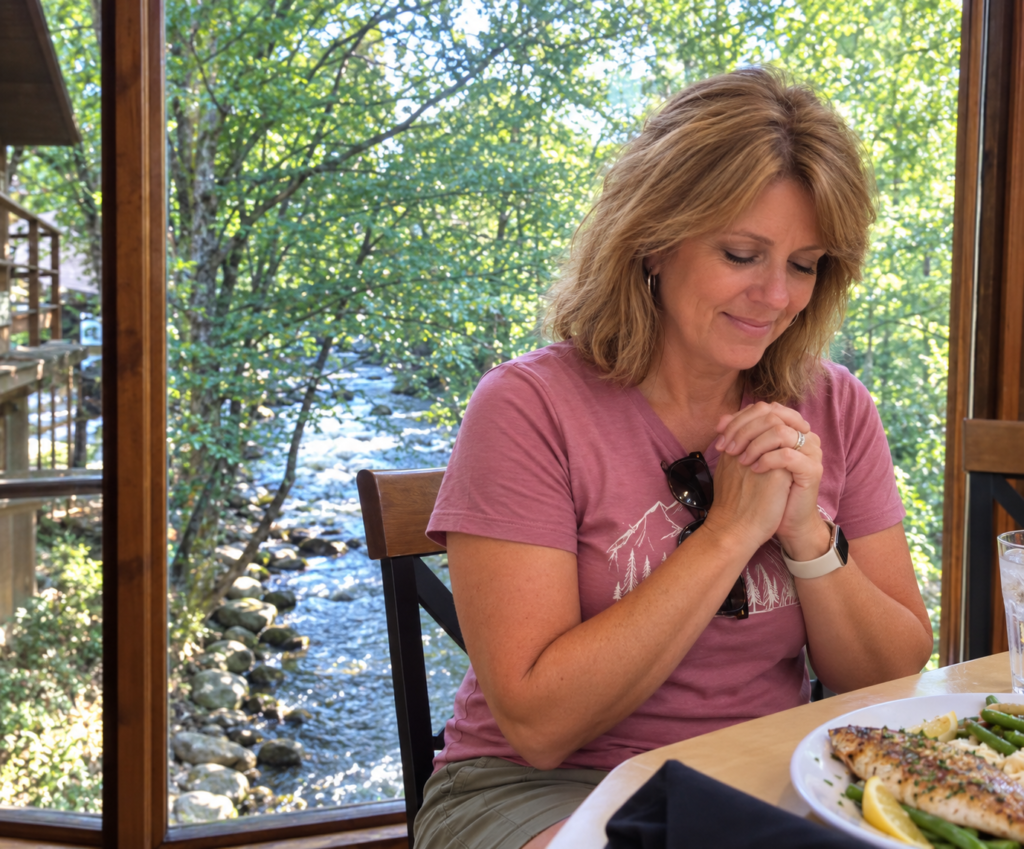 Woman saying grace before a fish dinner beside the Little Pigeon River